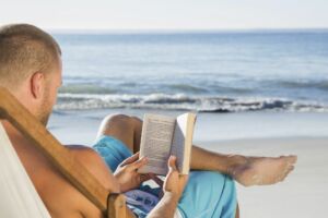 Handsome man reading a book on the beach